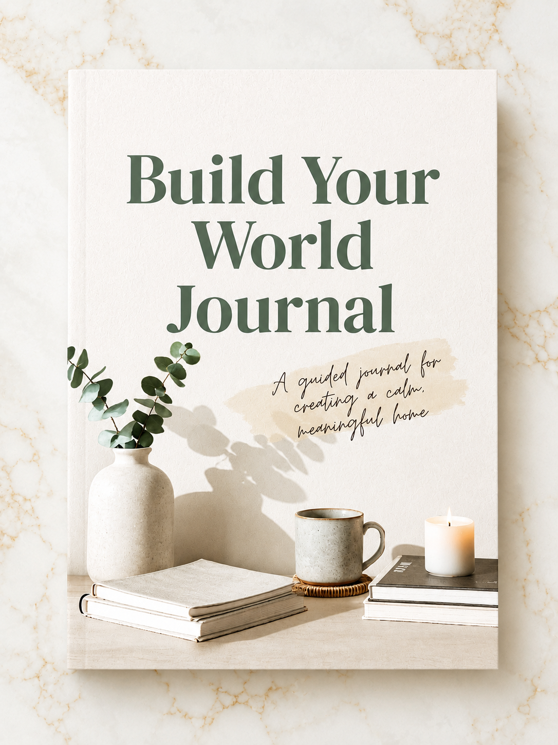 Book titled 'Build Your World Journal' on a marble surface with a vase and cup.