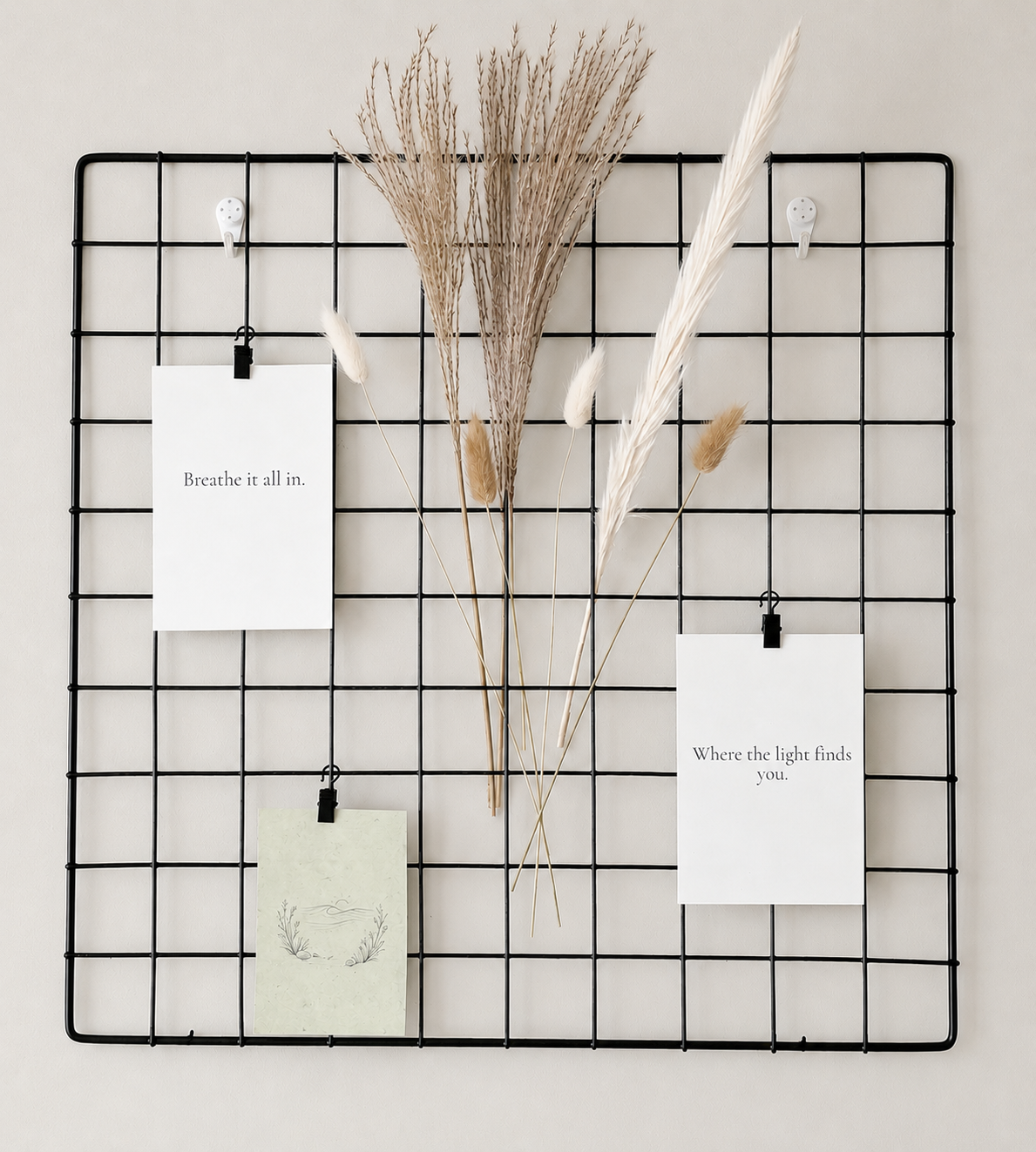 Black grid wall with dried plants and motivational cards on a light gray background